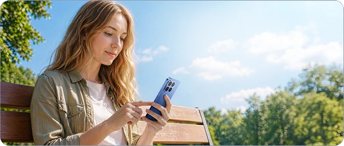 Kobieta korzystająca ze smartfona Xiaomi podczas siedzenia na ławce w parku