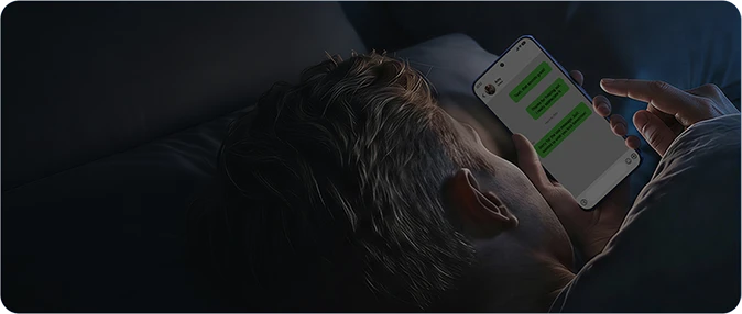 Mężczyzna korzystający ze smartfona Xiaomi w łóżku przy słabym oświetleniu