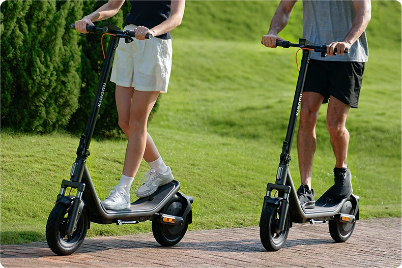 Dwie osoby jadące na Xiaomi Electric Scooter 6 po parkowej alejce