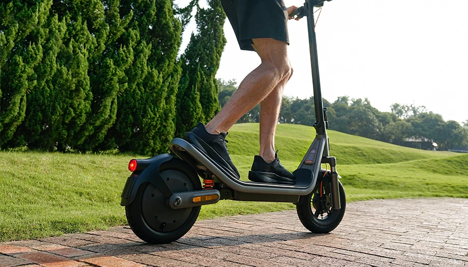 Zbliżenie na platformę i tylne koło Xiaomi Electric Scooter 6 podczas jazdy po parkowej alejce