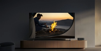Telewizor Xiaomi TV S Pro Mini LED 2026 wyświetlający wyraźny obraz ogniska i mężczyzny w ciemnym pomieszczeniu bez odbić na ekranie