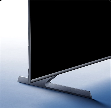 Zbliżenie na dolną część telewizora Xiaomi z metalową podstawą typu blade-edge na jasnym tle.